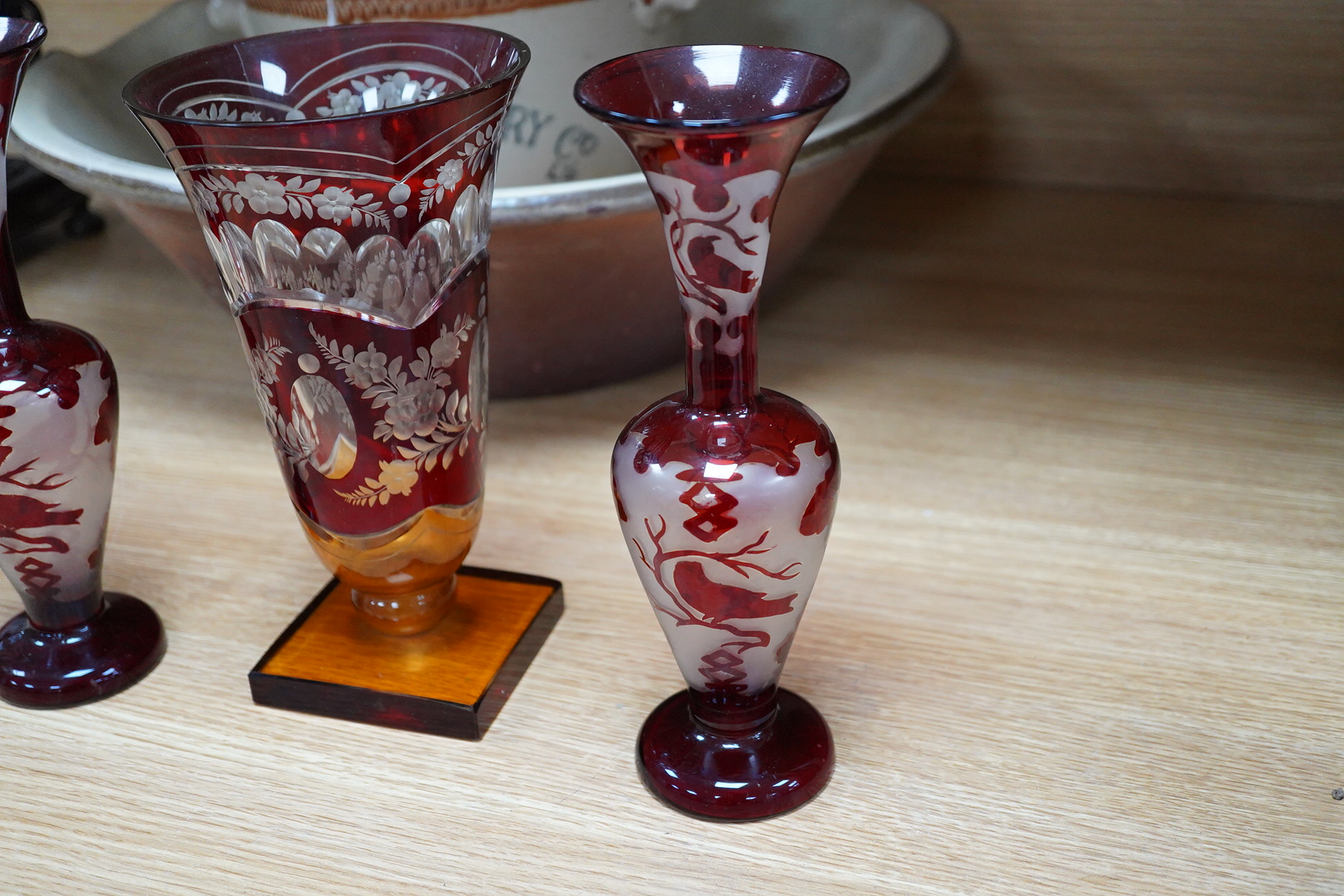 A Czechoslovakian red and amber cut glass square base vase, 21cm high and a pair of similar vases